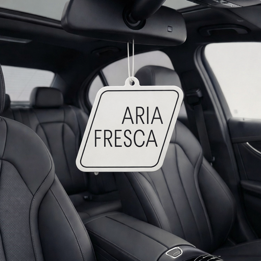 Car interior with 'Aria Fresca' air freshener hanging from the rear view mirror.